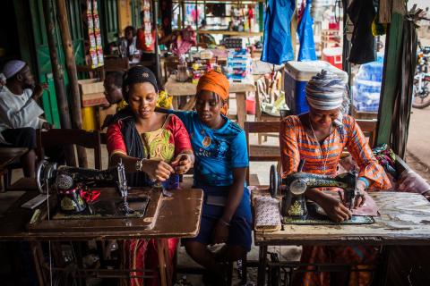 Three women sew on machines at a market in Guinea