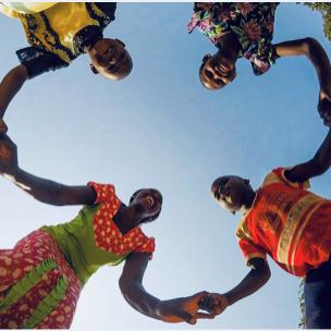 Photo of four people joining hands in a circle