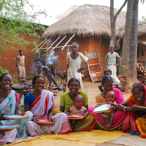 Photo of several women sitting on the ground together outside